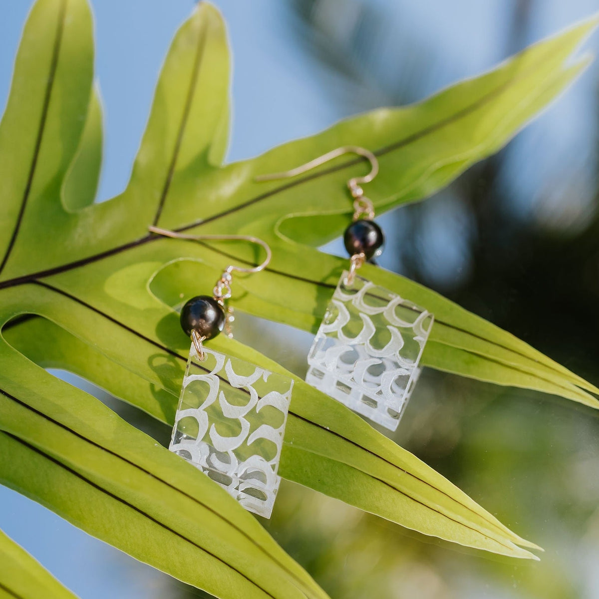 Earrings hanging on a leaf with a blurred natural background