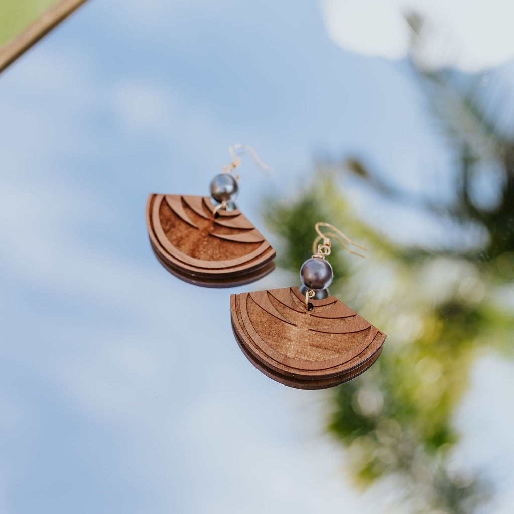 Wooden earrings with a reflective surface and blurred natural background